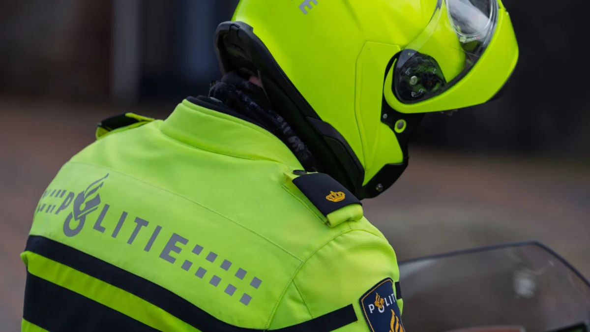 Nederlandse politieagent in neongele kleding tijdens dienst, met veiligheidsuitrusting.