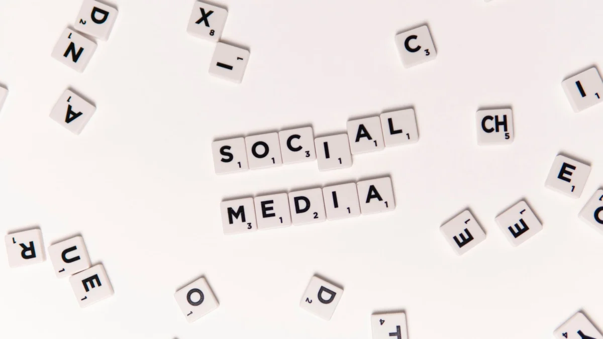 Bovenaanzicht van lettertegels die Social Media spellen met verspreide witte tegels op een oppervlak.