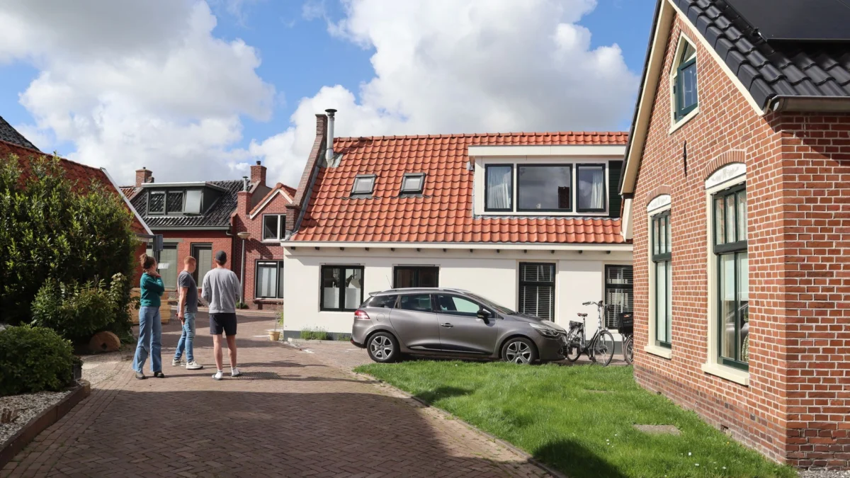Charmant uitzicht op traditionele Nederlandse huizen in Winsum, Nederland, met mensen die buiten staan.