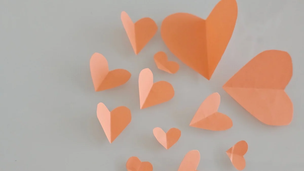 Een stilleven van roze papieren harten kunstzinnig gerangschikt tegen een zachte, gedempte achtergrond, perfect voor Valentijnsdag-thema's.