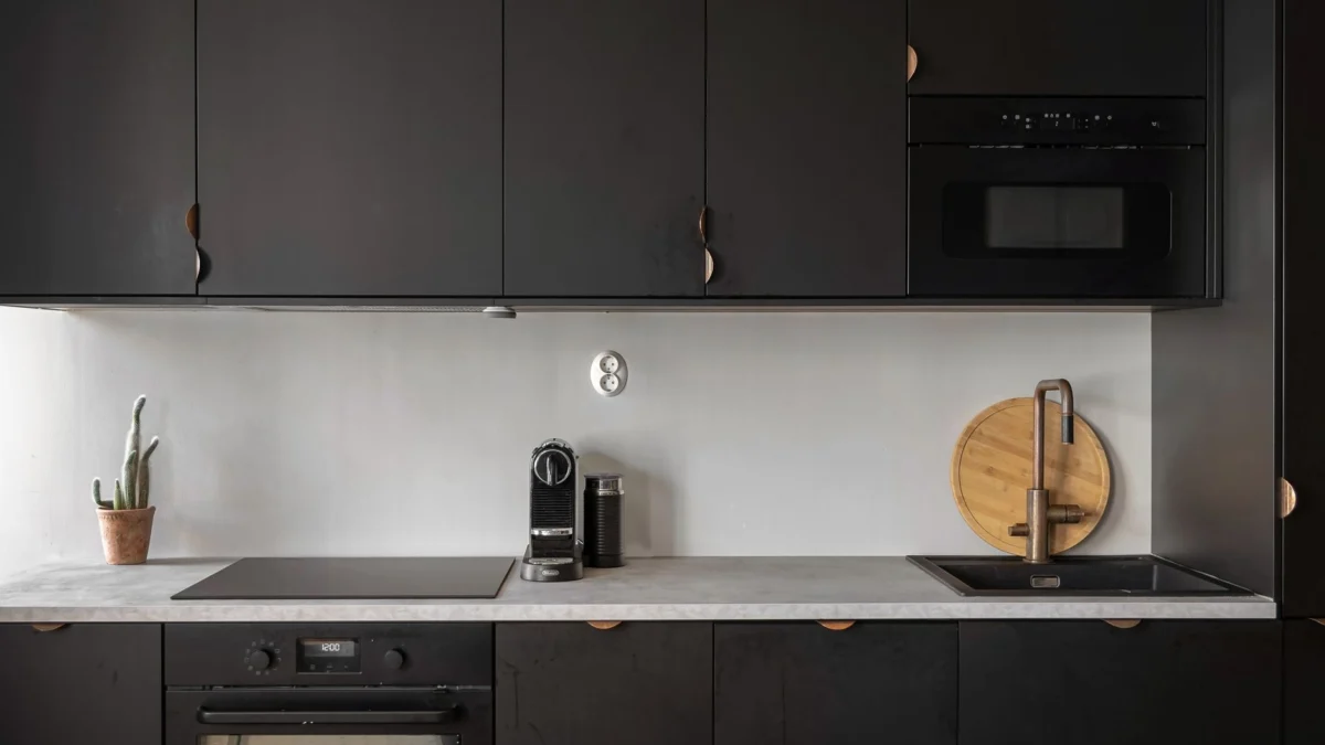 Strakke zwarte keukeninterieur met minimalistische kasten en moderne apparatuur.