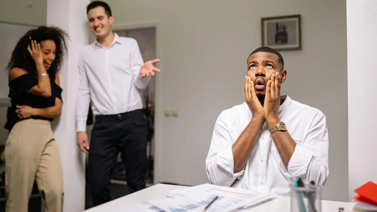 Zakeman in stress met lachende collega's in een moderne kantooromgeving.