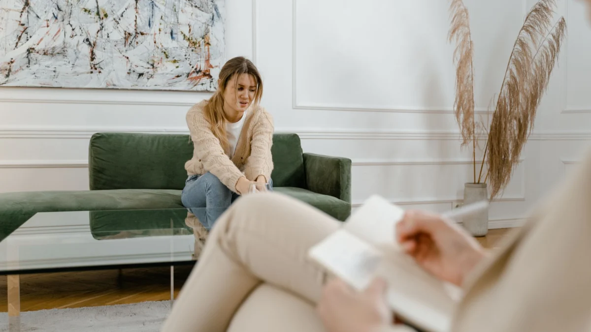 Een vrouw tijdens een therapiesessie in een moderne woonkamer, die bezorgdheid uitdrukt.