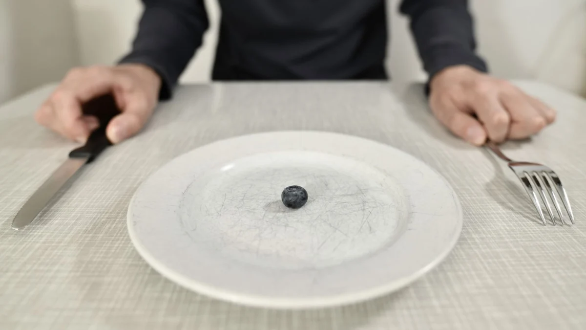 Een enkele blauwe bes op een gekradigd bord symboliseert een minimalistisch dieet en portiecontrole.