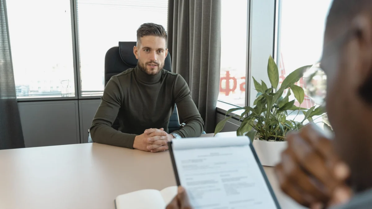 Professionele man in een coltrui aan een bureau tijdens een sollicitatiegesprek.