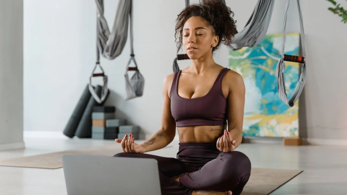 Vrouw die mediteert in een yoga studio met aerial yoga apparatuur, bevorderend voor ontspanning en fitness.
