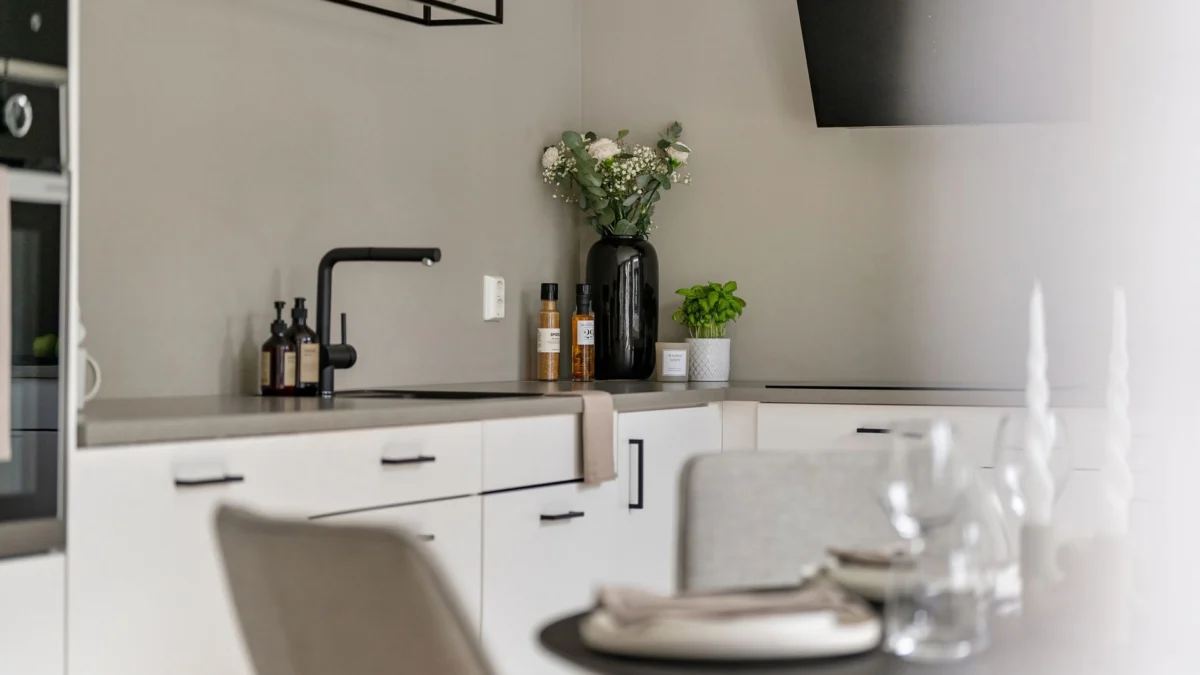 Strakke minimalistische keukeninterieur met decor, witte kasten en moderne apparaten.