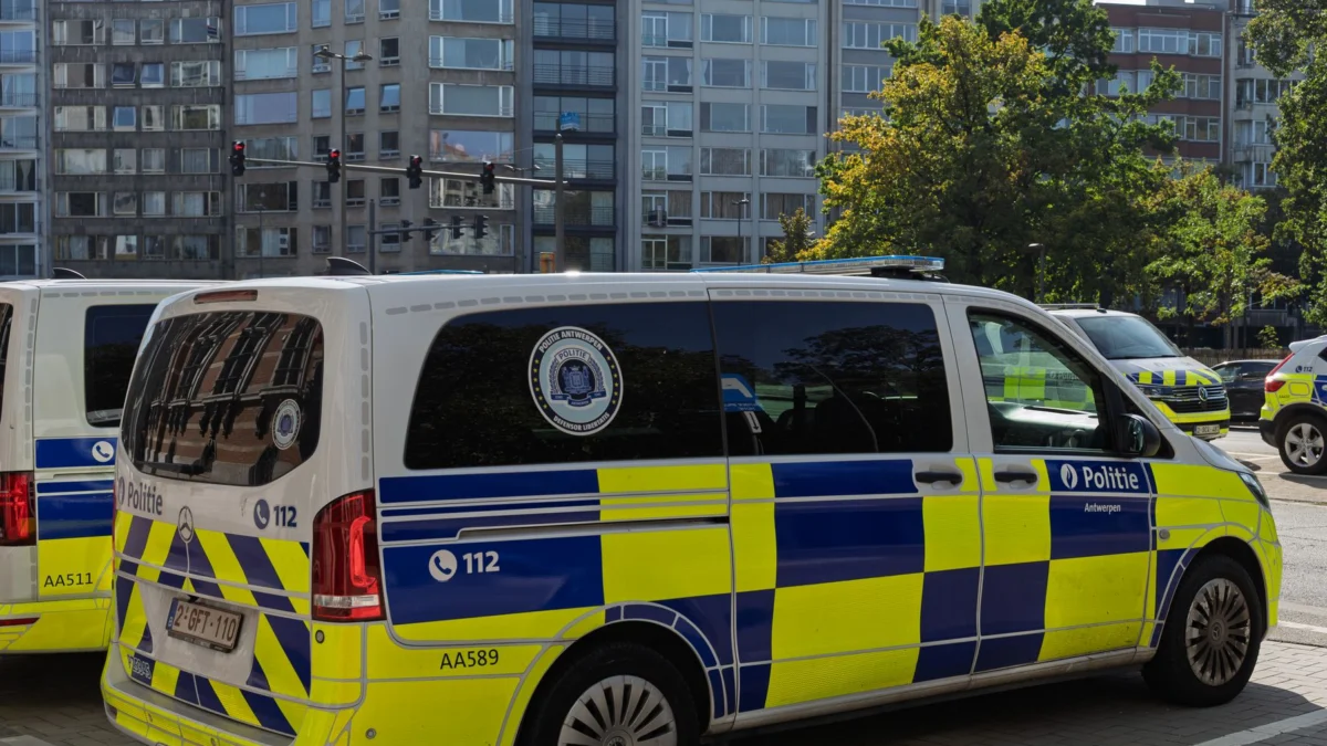 Politiewagens geparkeerd in Antwerpen, België, met stedelijke gebouwen op de achtergrond, wat de aanwezigheid van de politie benadrukt.